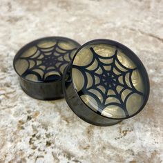 two black and gold spider web trinkets sitting on top of a marble surface