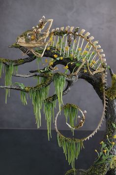 an animal skeleton is sitting on top of a tree branch with moss and yellow flowers