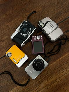 several different types of cameras sitting on a wooden floor next to each other and one has a camera attached to it