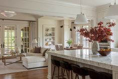 a kitchen island with chairs and a vase on it in front of a living room