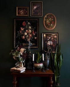 a table with flowers and candles on it in front of some framed pictures above them