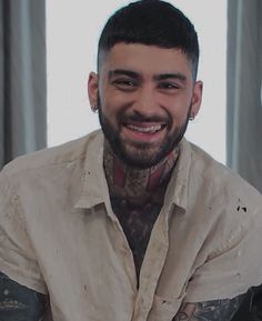 a man with tattoos smiling at the camera