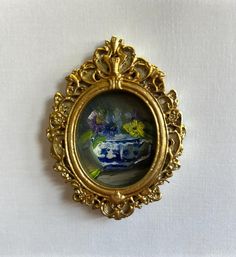 an ornate gold frame with a blue and white vase in the center on a white background