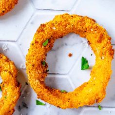 two fried onion rings with parsley on the top and one in the middle sitting on a white surface