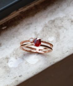 a close up of a ring with a red stone on the top and a diamond in the middle