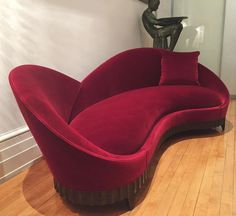 a red couch sitting on top of a hard wood floor