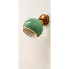 a green and gold wall light on a white wall