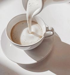 milk being poured into a cup of coffee