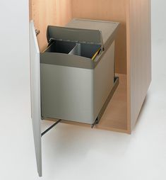 a metal trash can sitting inside of a wooden cabinet