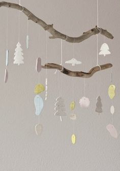 a tree branch is hanging from the ceiling with ornaments on it's branches and in front of a white wall