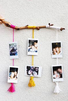 several pictures hanging on a wall with some tassels attached to the strings and two people