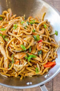 a pan filled with noodles and vegetables on top of a wooden table