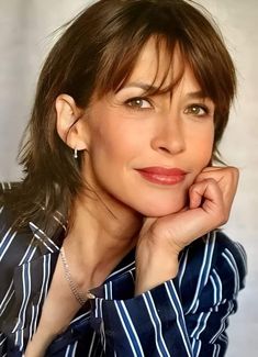 a close up of a person wearing a striped shirt and holding her hand on her chin