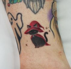 a cat with a red hat on it's head is shown in this tattoo