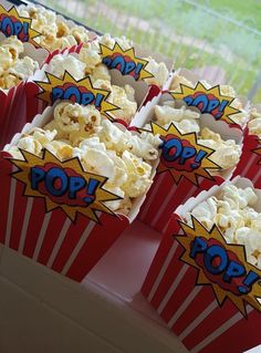 red and white popcorn boxes with pop written on them sitting in front of a window