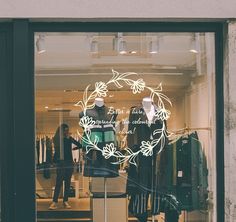 a store front window with clothes on display in the window and mannequins behind it