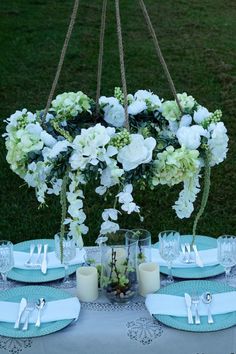 the table is set with white flowers and blue place settings for two people to eat