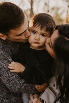 a man and woman kissing a little boy on the cheek while he is holding him