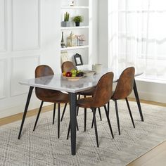 a dining table with four chairs and a bowl of fruit on it in front of a window