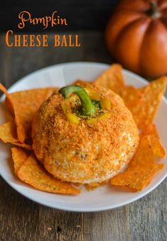 a white plate topped with cheese ball and tortilla chips next to a pumpkin