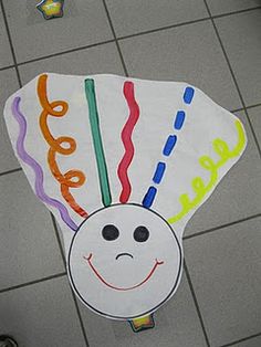 a paper kite with a smiley face on it's side and words written in different colors