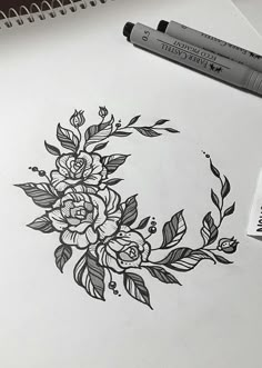 a drawing of flowers and leaves on paper next to a marker