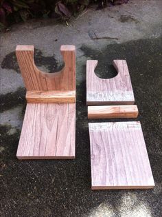 two pieces of wood sitting next to each other on top of a cement ground with plants in the background