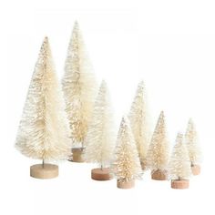 small white christmas trees lined up in a row on wooden bases, against a white background