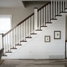 a white staircase with pictures on the wall and carpeted floor in front of it