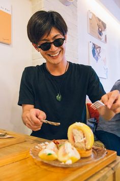 a man sitting at a table with food in front of him and eating from a plate