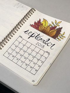 an open planner with autumn leaves on it