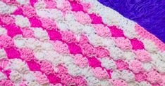 a crocheted blanket with pink and white stripes