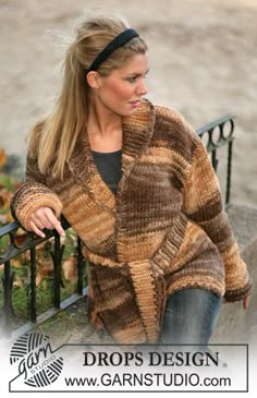 a woman sitting on a bench wearing a brown and black striped cardigan sweater over her head