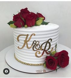 a white cake with gold lettering and red roses