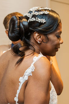 the back of a bride's dress as she fixes her hair