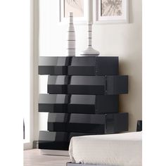 a tall black shelf with two lamps on it's sides next to a bed