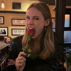 a woman holding a rose up to her mouth