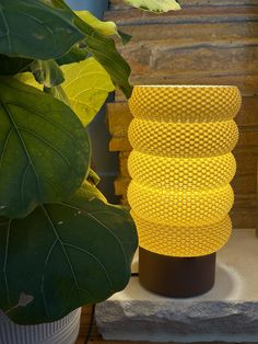 a yellow vase sitting on top of a table next to a plant