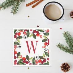 the letter w is surrounded by holly and berries, pine cones, cinnamon sticks, and spices