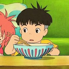 two young children sitting at a table eating food with chopsticks in front of them