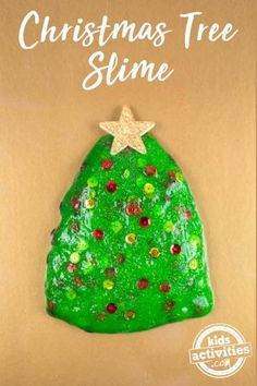 a green christmas tree slime is sitting on top of a brown surface with the words,