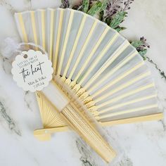 a white and yellow fan sitting on top of a table next to some flowers in front of it