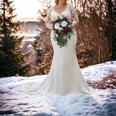 a woman is standing in the snow with her wedding dress on and holding a bouquet