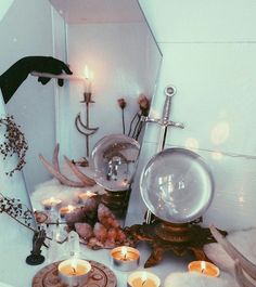 candles are sitting on the floor in front of a mirror and other items that have been placed around it