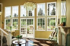 a living room filled with lots of windows next to a fire place and table in front of it