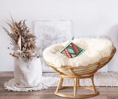 a chair with a pillow on it next to a vase and some dried plants in the background