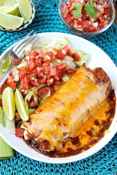 a white plate topped with mexican enchilada next to a bowl of salsa