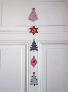 three christmas trees hanging from the side of a white door with red and blue decorations