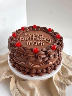 a chocolate birthday cake with the words happy birthday mom on it sitting on a table