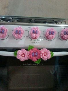 pink cupcakes sitting on top of an oven with green leaves and purple flowers